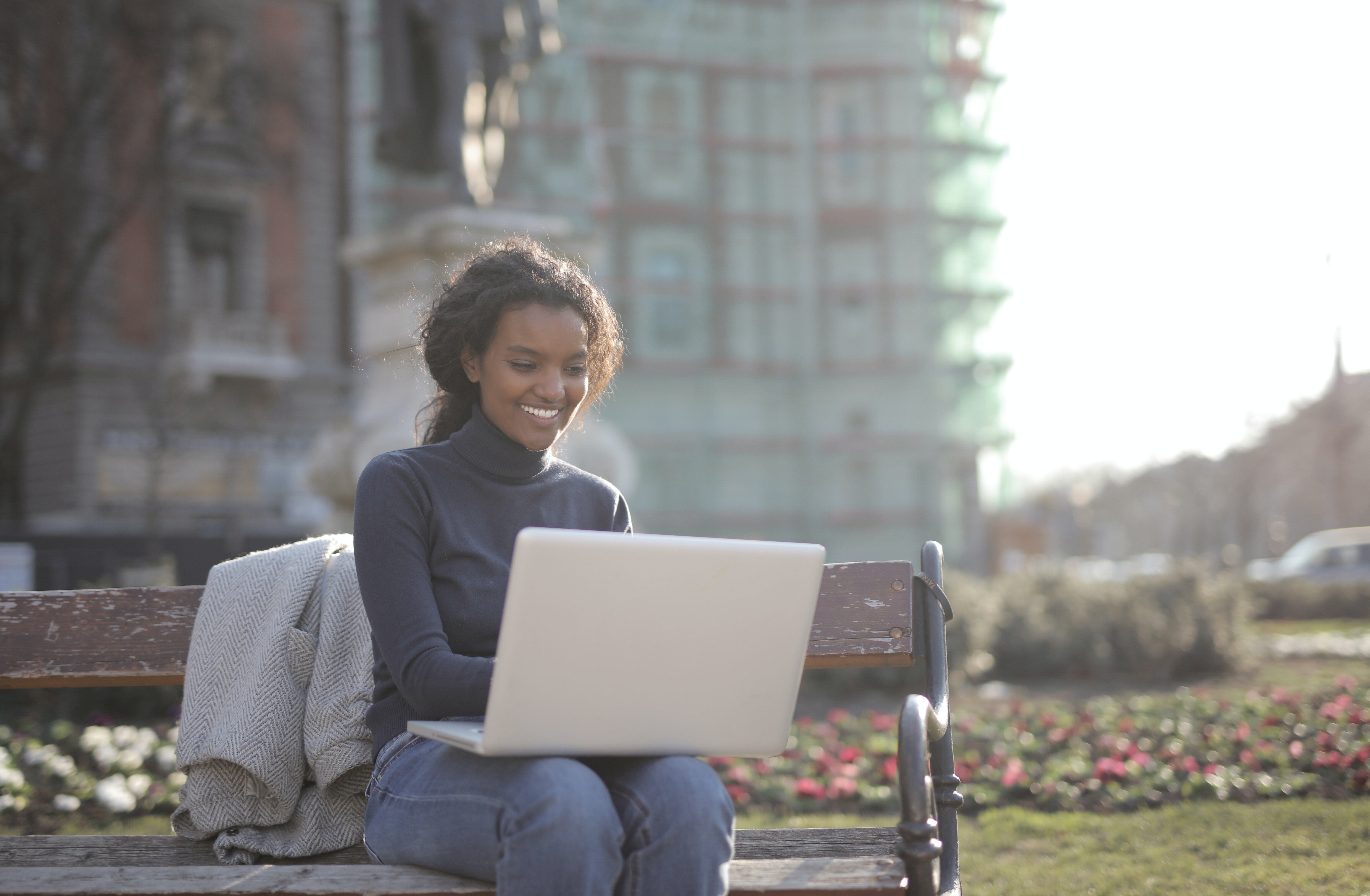Women sitting on a bench working on a laptop