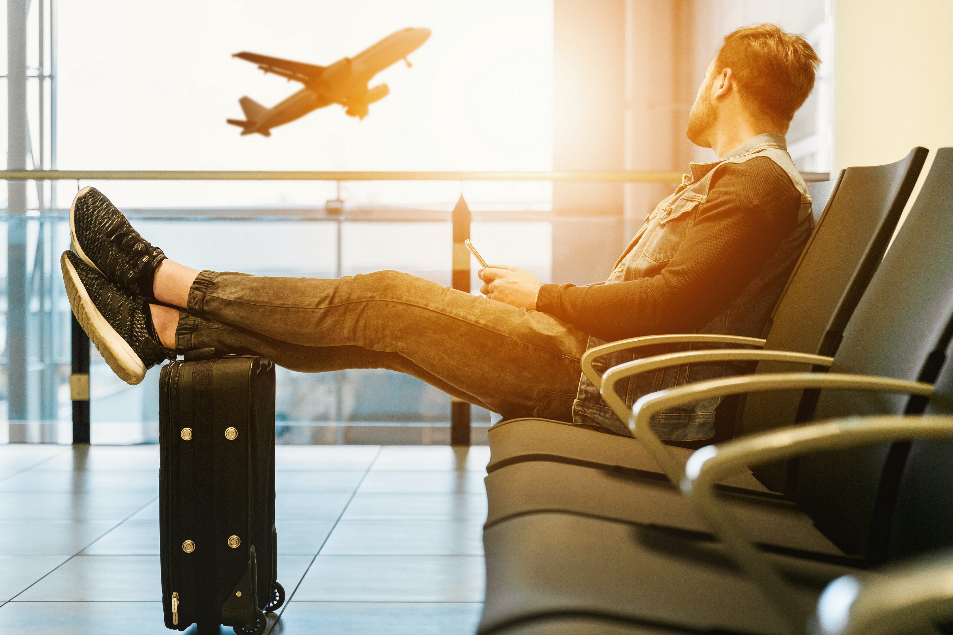 Man waiting in airport with feet on his bag